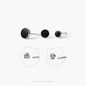 May include: Three silver stud earrings with black circular insets are displayed. The image also shows the back of a star-shaped earring and a silver ball earring with a screw post. The brand name "SHEMISLI JEWELS" is at the bottom.