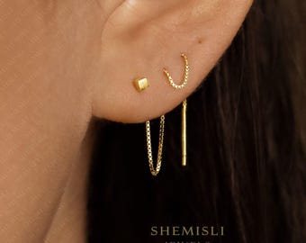 May include: A close-up shot of an ear featuring three gold earrings. There's a small square stud, a chain hoop, and a chain drop earring. The brand name "SHEMISLI JEWELS" is displayed at the bottom of the image.