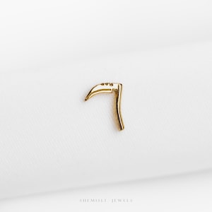 Peut inclure: Un petit charme en forme de faux de couleur or. Le charme a une lame incurvée et une poignée. La faux est posée sur un fond blanc. Le texte "SHEMISLI JEWELS" est au bas de l'image.