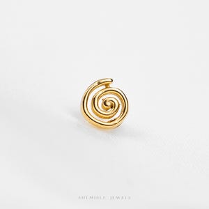 May include: A gold spiral stud earring. The earring has a coiled design with a rounded top, set against a white background. The brand name "SHEMISLI JEWELS" is at the bottom.