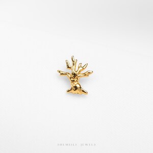 May include: A gold-coloured tree-shaped jewellery piece. The jewellery has a textured surface and a detailed design, with branches extending outwards. The piece is set against a white background. The brand name "SHEMISLI JEWELS" is at the bottom.