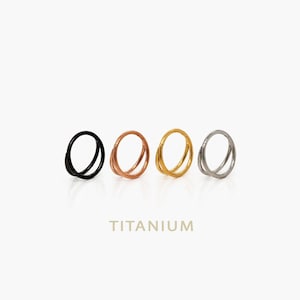 Peut inclure: Quatre anneaux de nez à double cercle en noir, or rose, or et argent. Les anneaux sont en titane et sont présentés sur un fond blanc. Le mot "TITANIUM" est imprimé en or en dessous.