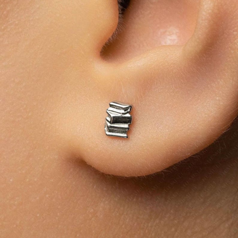 A close-up view of a person's ear, showing a small silver earring in the earlobe.