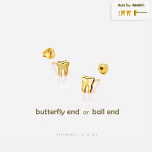 Peut inclure: Boucles d'oreilles dorées en forme de dents. L'image présente deux clous en forme de dents, un fermoir papillon et un fermoir boule. Le texte sur l'image indique "butterfly end or ball end" et "style by shemisli".