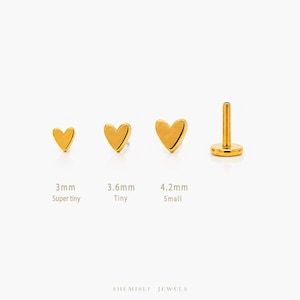 Peut inclure: Boucles d'oreilles dorées en forme de cœur, disponibles en trois tailles : 3 mm, 3,6 mm et 4,2 mm. Les boucles d'oreilles sont étiquetées "Super tiny", "Tiny" et "Small". Une boucle d'oreille a une tige pour le perçage. La marque "SHEMISLI JEWELS" est en bas.