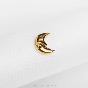 May include: A gold-coloured crescent moon charm with a smiling face. The charm is set against a white background. The text "SHEMISLI JEWELS" is at the bottom of the image.
