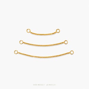 Peut inclure: Trois rallonges de chaîne dorées de différentes longueurs, chacune avec un petit anneau aux deux extrémités. Les chaînes ont un design texturé en forme de boîte. Le fond est blanc uni. La marque "SHEMISLI JEWELS" est en bas.