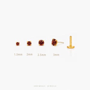 May include: A selection of gold stud earrings featuring round, red gemstones. The earrings are shown in sizes 1.5mm, 2mm, 2.5mm, and 3mm. One earring is shown from the side. The brand name "SHEMISLI JEWELS" is at the bottom.