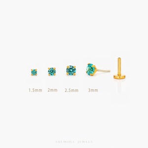 May include: Gold stud earrings with teal gemstones, displayed in sizes 1.5mm, 2mm, 2.5mm, and 3mm. The image shows a side view of an earring and a flat-back post. The earrings are presented against a white background.