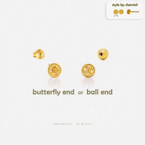 May include: Gold stud earrings, featuring a butterfly design and ball-shaped studs. The image includes the text "butterfly end or ball end" and "style by shemisli". The earrings are presented on a white background.