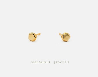 Könnte beinhalten: Ein Paar kleine, goldfarbene Ohrstecker mit einem geometrischen, facettierten Design. Die Ohrringe sind vor einem weißen Hintergrund platziert. Der Text "SHEMISLI JEWELS" ist darunter zu sehen.