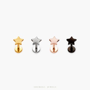 Peut inclure: Quatre piercings pour les lèvres en forme d'étoile, de couleur or, argent, or rose et noir. Chaque piercing est composé d'une étoile et d'un dos plat et rond. Les piercings sont présentés sur fond blanc. La marque "SHEMISLI JEWELS" est en bas.