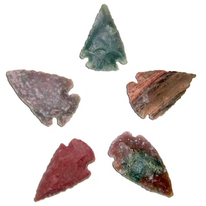 May include: Five handcrafted stone arrowheads in various colors, including green, red, and brown. Each arrowhead has a unique shape and texture, showcasing natural variations in the stone. The arrowheads are arranged against a white background.