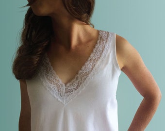 May include: White sleeveless tank top with a lace trim around the neckline.