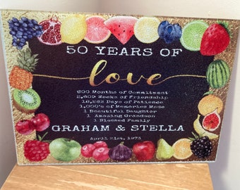 May include: A black and gold cutting board with a fruit design and the text "50 Years of Love" and "Graham & Stella April 21st, 1973".