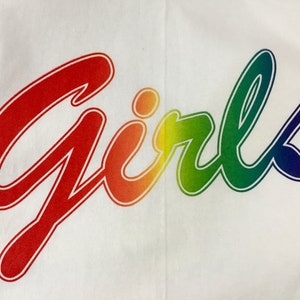 May include: The word "Girls" in a rainbow gradient, outlined in red, is displayed on a white background. The text is in a cursive font, with the colors blending from red to purple.