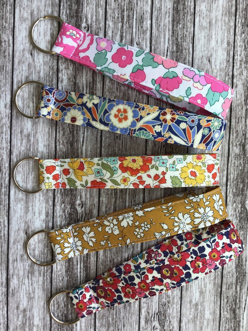 Puede incluir: Cinco llaveros coloridos con patrones florales. Cada llavero tiene un anillo de metal plateado y est&aacute; hecho de tela con una variedad de estampados florales.