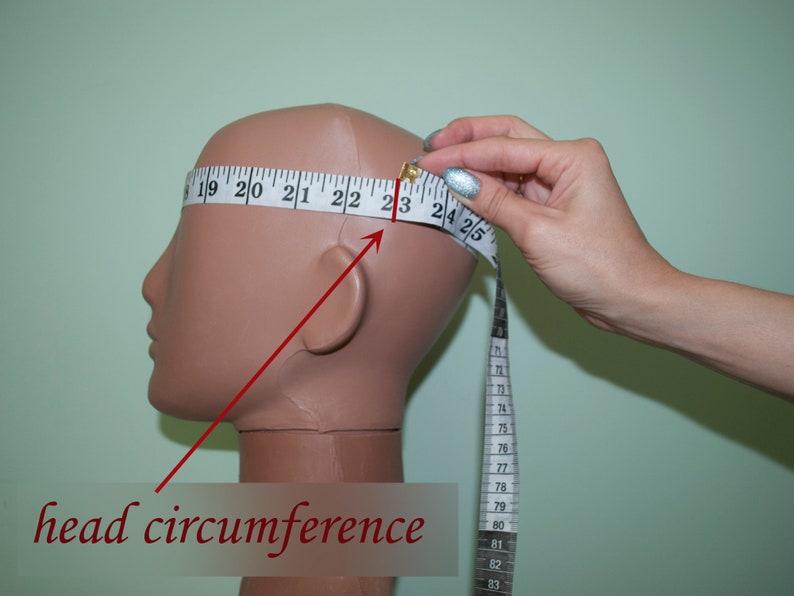 May include: A white measuring tape is wrapped around a mannequin's head to measure the head circumference. The tape reads "19 20 21 22 23 24 25" and "head circumference".