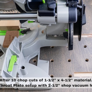 May include: A close-up of a gray and green chop saw with a wood block in the blade. The saw is set up with a dust collection system and a throat plate. The text reads "After 10 chop cuts of 1-1/2" x 4-1/2" material. DC Throat Plate setup with 2-1/2" shop vacuum hose."