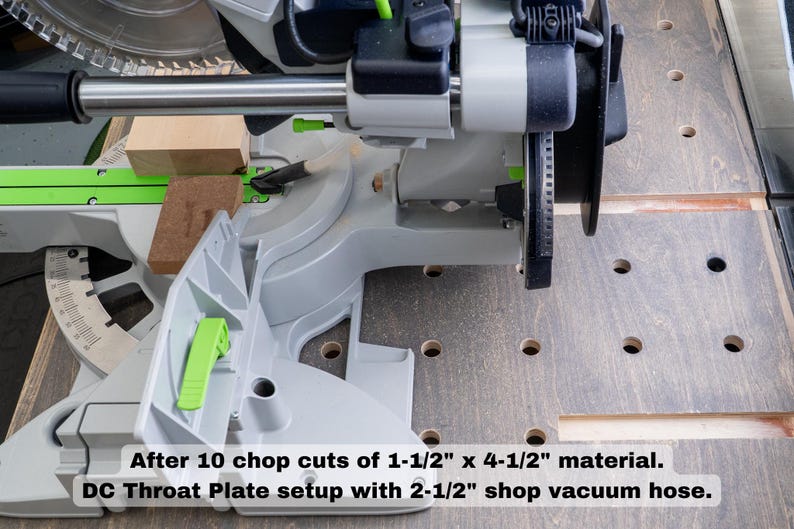 May include: A close-up of a gray and green chop saw with a wood block in the blade. The saw is set up with a dust collection system and a throat plate. The text reads "After 10 chop cuts of 1-1/2" x 4-1/2" material. DC Throat Plate setup with 2-1/2" shop vacuum hose."