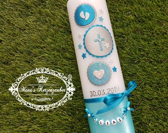 May include: A white candle decorated with blue and silver accents. The candle features a cross, stars, and a heart design. The date "30.03.2019" is printed on the candle. A blue ribbon and a beaded strand with the name "LIAS" are attached.