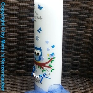 Peut inclure: Une bougie blanche d&eacute;cor&eacute;e de papillons bleus, d'un hibou et d'un oiseau perch&eacute; sur une branche. La bougie a un ruban bleu et le texte "Zur Taufe" et l'ann&eacute;e 2005.