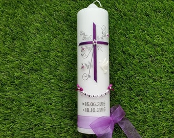 May include: A white pillar candle decorated with a purple cross, floral accents, and the name "ANNA-LENA" spelled out on a string of beads. The candle also features the dates "16.06.2015" and "18.10.2015". A purple ribbon is at the base.