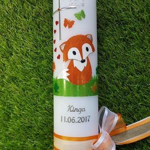 May include: White candle decorated with a glittery orange fox, butterflies, and hearts. The candle has the text "Zur Taufe" and the name "Kinga" with the date "11.06.2017". An orange and white ribbon is tied around the base.
