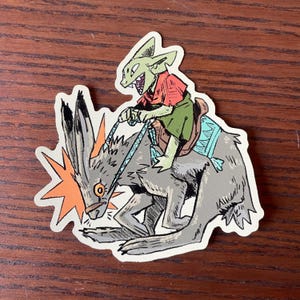 May include: A sticker featuring a cartoon illustration of a green goblin riding a gray, rabbit-like creature. The goblin wears a red shirt and green pants. The rabbit has an orange burst on its head.