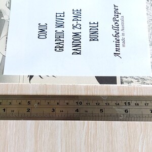 Puede incluir: Un primer plano de una regla que mide una pila de libros de bolsillo. Los libros de bolsillo est&aacute;n etiquetados como "Comic", "Graphic Novel", "Random 25-Page Bundle" y "AnniebelloPaper made in Australia".