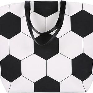 Puede incluir: Un bolso tote blanco con un dise&ntilde;o de bal&oacute;n de f&uacute;tbol negro. El bolso tiene asas negras y forma rectangular. El dise&ntilde;o del bal&oacute;n de f&uacute;tbol est&aacute; formado por formas hexagonales negras y blancas.