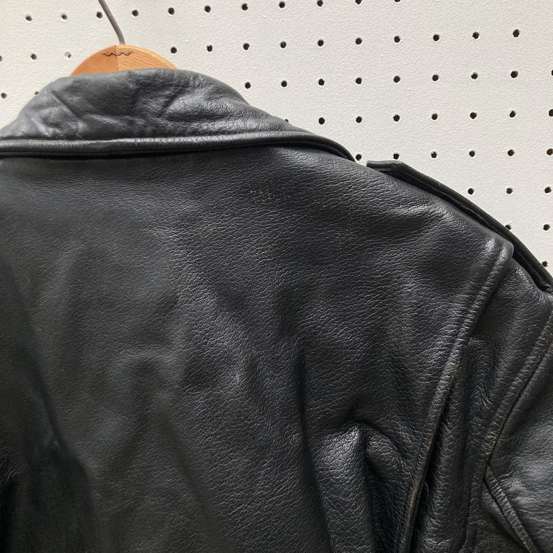 May include: Black leather jacket with a zip fastening and a collar. The jacket has a smooth, textured surface.