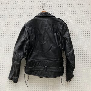 May include: Black leather motorcycle jacket with a zip fastening, a belt at the waist, and lace-up details on the sides.