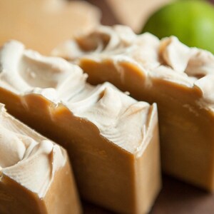 May include: Four bars of handmade soap with swirls of white and brown. The soap is arranged in a row on a wooden surface.