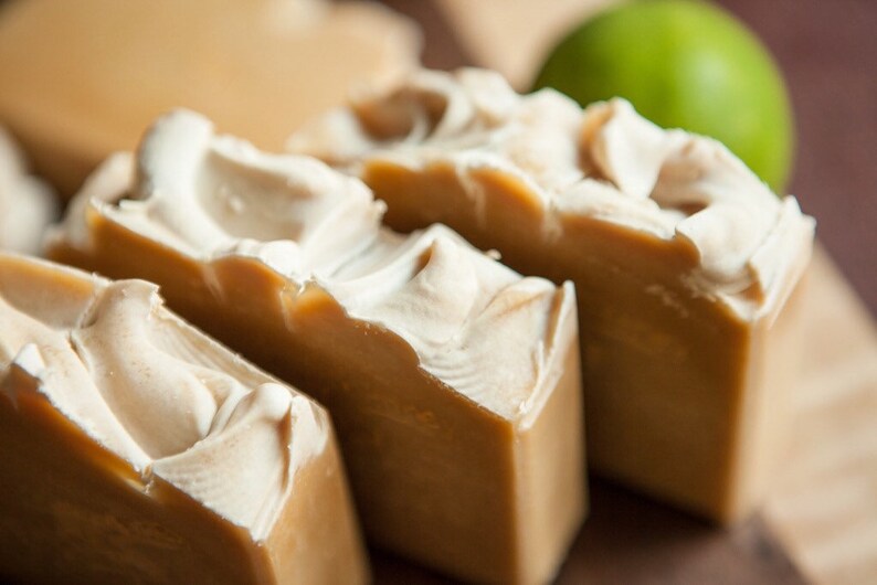 May include: Four bars of handmade soap with swirls of white and brown. The soap is arranged in a row on a wooden surface.