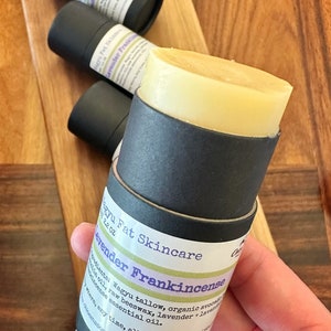 May include: A black and white label on a black tube reads "Wagyu Fat Skincare Lavender Frankincense 1.2 oz". The label lists ingredients: "Wagyu tallow, organic avocado oil, raw beeswax, lavender + frankincense essential oil." The label also states "any time, all natural skin moisturiser" and "loemasonsoapcompany.com".