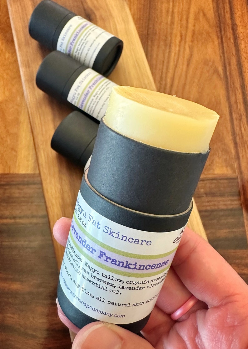 May include: A black and white label on a black tube reads "Wagyu Fat Skincare Lavender Frankincense 1.2 oz". The label lists ingredients: "Wagyu tallow, organic avocado oil, raw beeswax, lavender + frankincense essential oil." The label also states "any time, all natural skin moisturiser" and "loemasonsoapcompany.com".