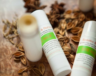 May include: Three white tubes of lip balm with green and orange labels. The labels read "Tomato & Carrot Lip Balm" and "Tomato & Green Tea Lip Balm".