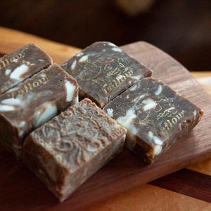 May include: Five bars of brown soap with white swirls and gold lettering that reads "Yellow" on a wooden surface.