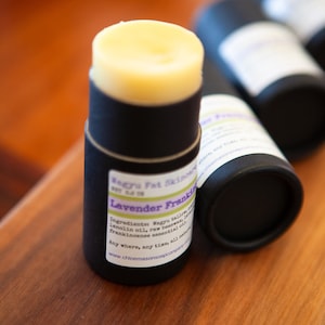 May include: A black tube with a white label that reads "Wagyu Fat Skinowy Lavender Frankincense" and lists ingredients including Wagyu tallow, lanolin oil, raw beeswax, and frankincense essential oil. The tube is filled with a light yellow balm.