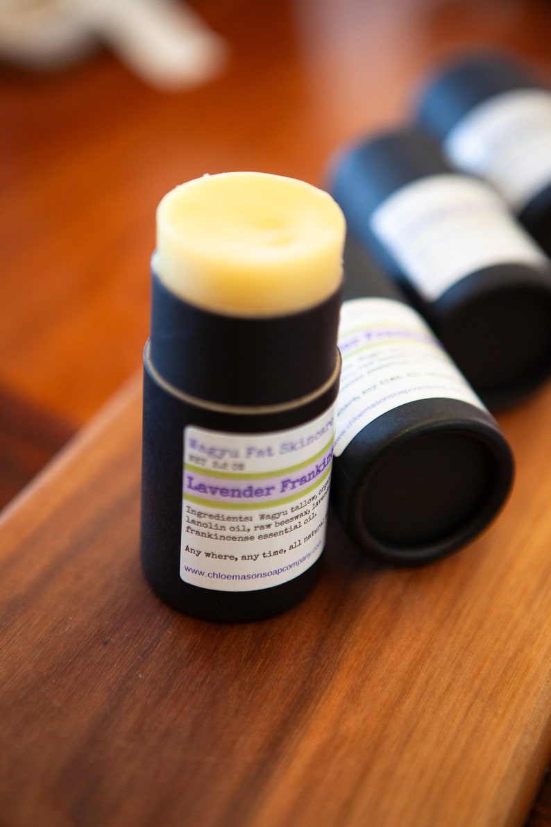 May include: A black tube with a white label that reads "Wagyu Fat Skinowy Lavender Frankincense" and lists ingredients including Wagyu tallow, lanolin oil, raw beeswax, and frankincense essential oil. The tube is filled with a light yellow balm.