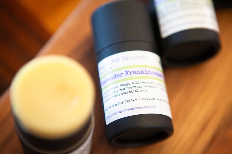 May include: A black tube of lavender and frankincense balm with a white label that reads "Fat Skincare Lavender Frankincense" and lists the ingredients: Wagyu tallow, organic beeswax, lavender and frankincense essential oil. The label also says "where, any time, all natural skin care" and includes the website address www.choemarsonsoapcompany.com.