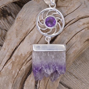 May include: A silver pendant with a purple amethyst stone set in a circular design. The pendant is attached to a silver chain.
