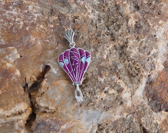 May include: A silver charm in the shape of a hot air balloon with purple and white enamel detailing.