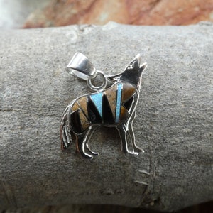May include: Sterling silver pendant featuring a howling wolf design. The wolf is inlaid with turquoise, black onyx, and tiger eye stones.