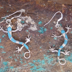May include: A pair of silver earrings with turquoise and mother of pearl inlay, shaped like lizards.