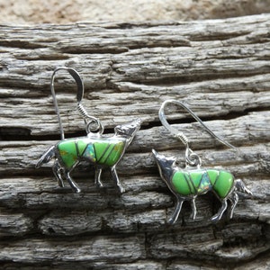 May include: A pair of sterling silver earrings featuring howling wolf designs. The wolves are inlaid with green turquoise and opal stones.