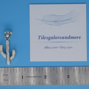 May include: A silver-toned cactus pendant with white and pink opal-like inlays. The pendant is next to a ruler and a card with the text "Tilesgaloreandmore" and "eBay.com~Etsy.com" on a blue background.