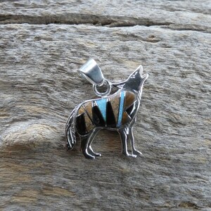 May include: A silver pendant in the shape of a howling wolf, inlaid with turquoise, black onyx, and tiger's eye stones.