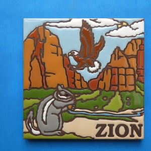 May include: Square ceramic tile featuring a colorful illustration of Zion National Park. The design includes a flying eagle, a chipmunk, and the word "ZION" at the bottom. The background depicts the park's landscape with mountains and a blue sky.
